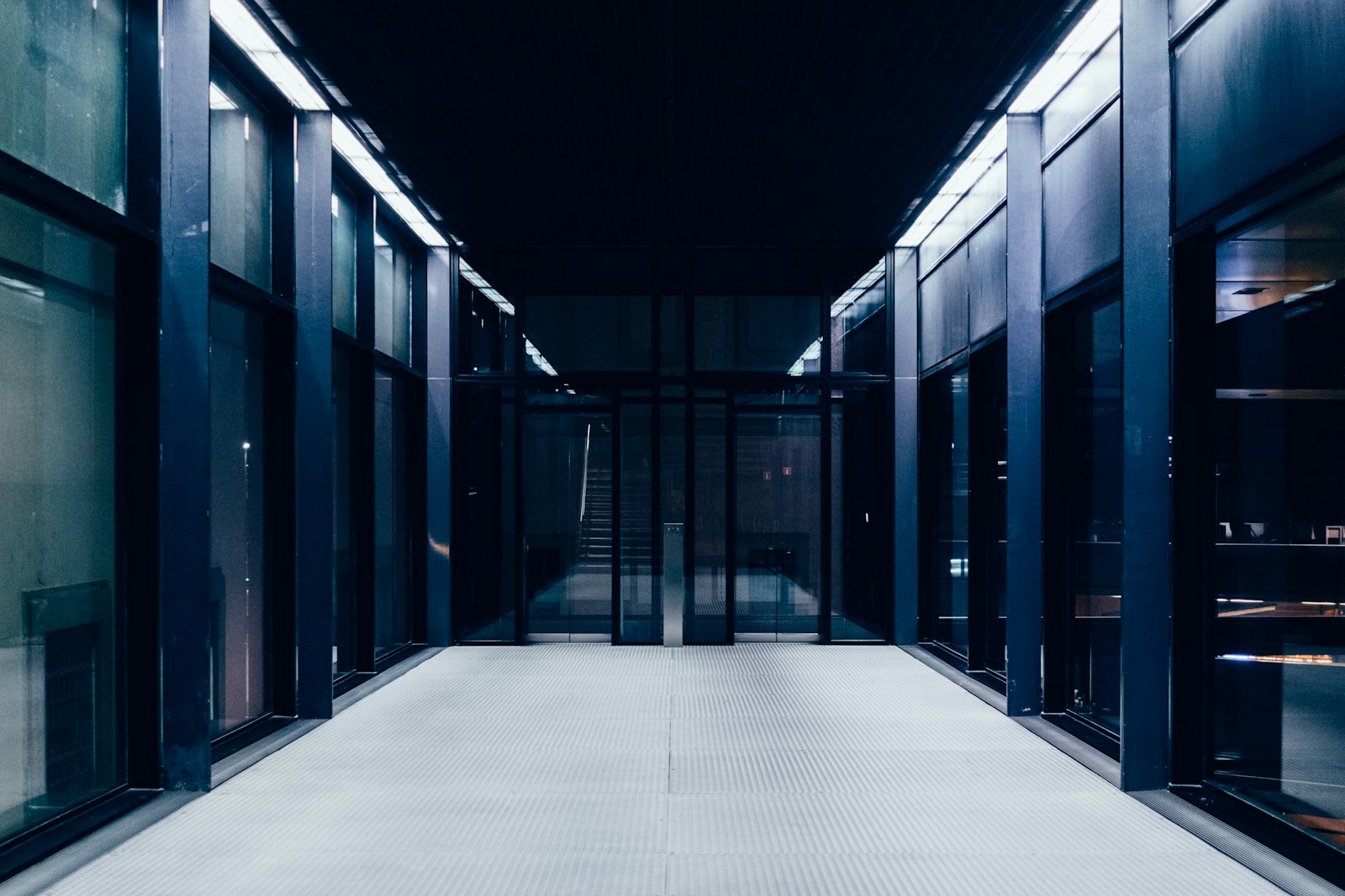 A long hallway with glass doors leading to rooms beyond